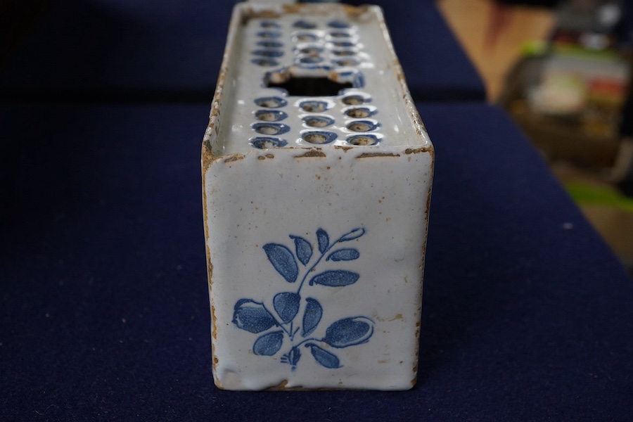 An 18th century English delftware flower brick, 15cm wide, 8cm high. Condition - edges chipped and larger chip to one corner, usual for pottery type, use and age